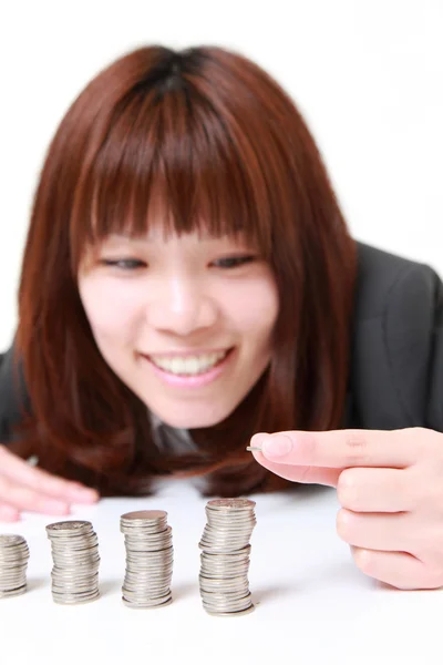 Businesswoman put coins to stack of coins — Stock Photo, Image