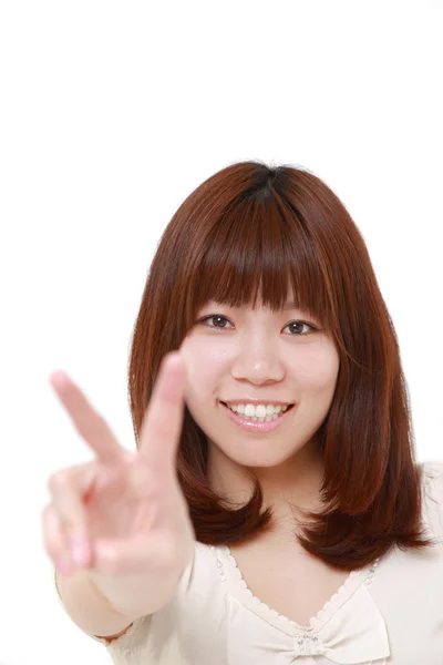 Jovem mulher japonesa mostrando um sinal de vitória — Fotografia de Stock