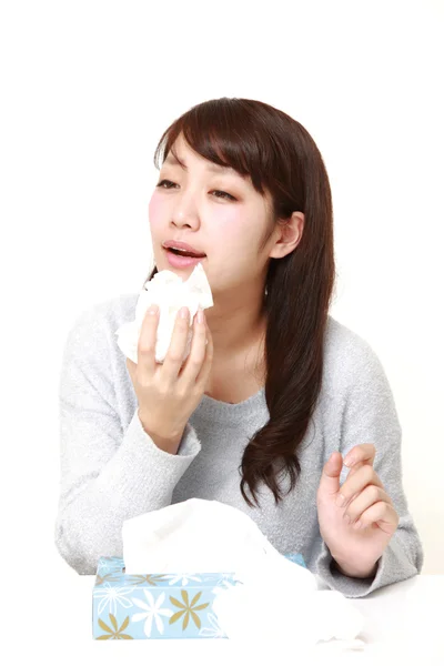 Молодая женщина с аллергией чихает в ткани — стоковое фото