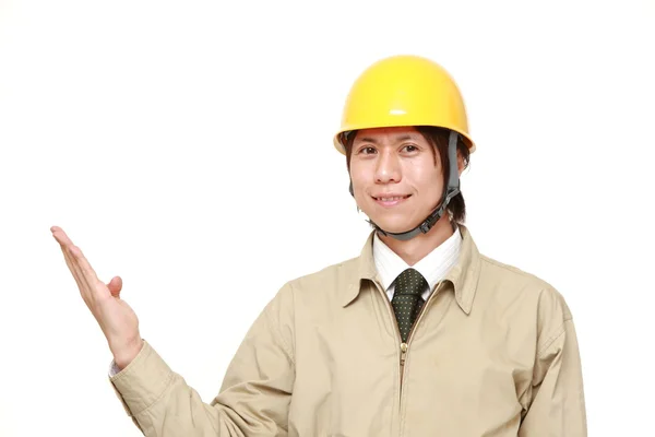 Jovem trabalhador da construção japonesa apresentando e mostrando algo — Fotografia de Stock