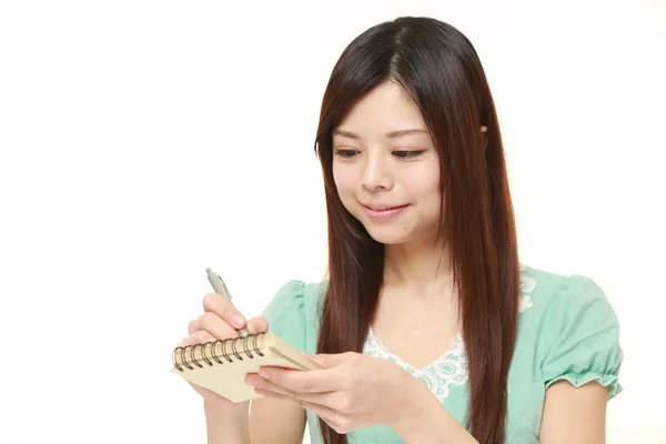Unga japanska kvinnan skriver i anteckningsboken — Stockfoto