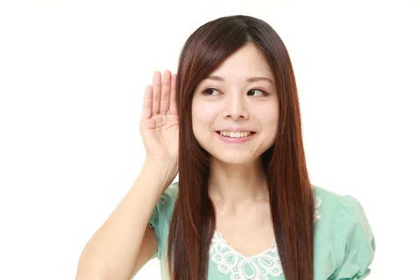 Joven japonesa con la mano detrás de la oreja escuchando atentamente — Foto de Stock