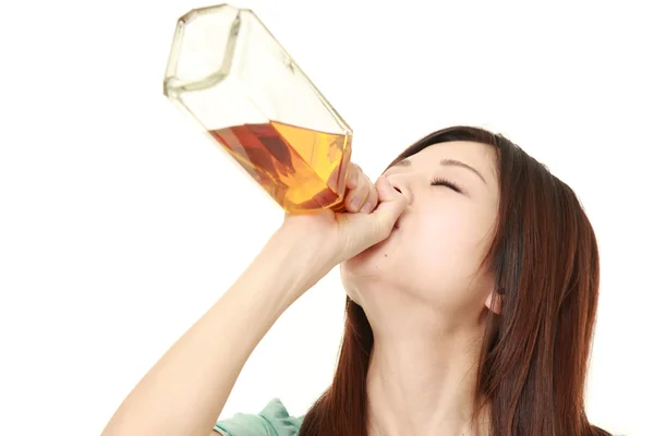 Young Japanese woman drinking straight from a bottle — Stock Photo, Image