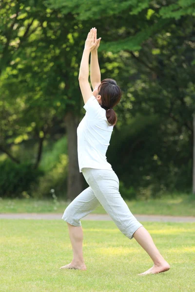 Japonesa mujer fuera haciendo yoga guerrero yo pose — Foto de Stock