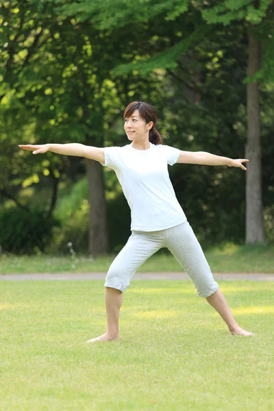 Japonesa mujer afuera haciendo yoga warrior II pose —  Fotos de Stock