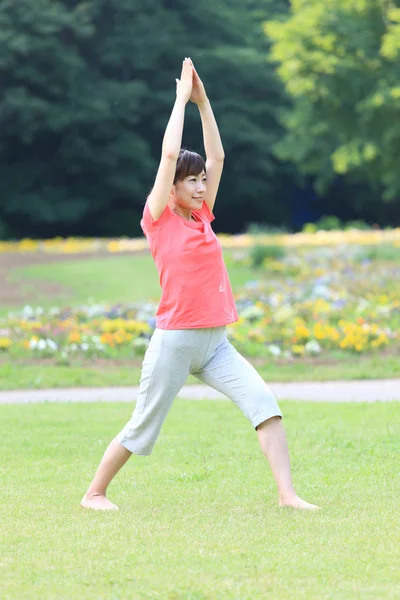 Japonesa mujer fuera haciendo yoga guerrero yo pose — Foto de Stock
