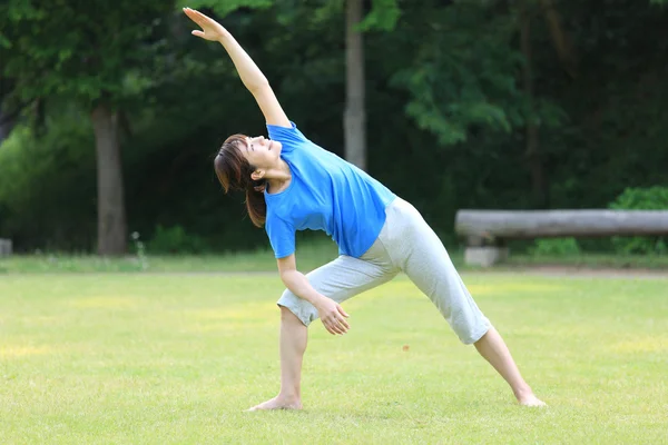 Japonês mulher fora fazendo ioga triângulo pose — Fotografia de Stock