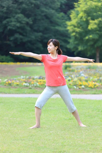 Japonês mulher lá fora fazendo ioga guerreiro II pose — Fotografia de Stock