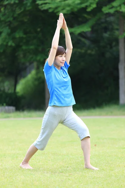 Japonesa mujer fuera haciendo yoga guerrero yo pose — Foto de Stock