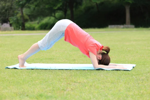 Japonês mulher lá fora fazendo ioga Downward-Facing Dog — Fotografia de Stock