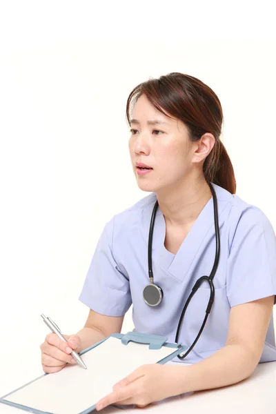 Japoński kobiece kobieta lekarz z klinicznych rekord rozmawia z jej pacjenta — Zdjęcie stockowe