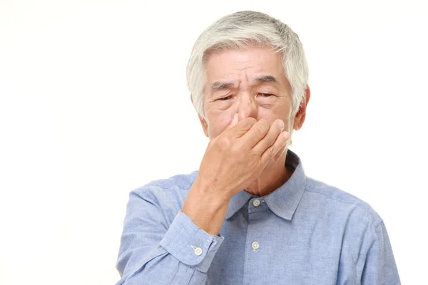 Senior japonés hombre sosteniendo su nariz a causa de un mal olor —  Fotos de Stock