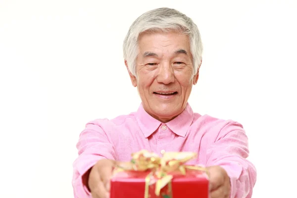 Старший японский мужчина предлагает подарок — стоковое фото