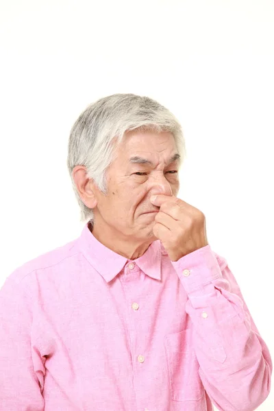 Senior japonés hombre sosteniendo su nariz a causa de un mal olor —  Fotos de Stock