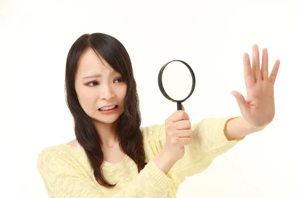 Shocked young woman looking through a magnifying glass her nails — Stock Photo, Image