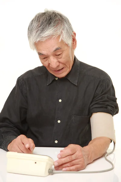 Senior japonés hombre chequeando su presión arterial shocked —  Fotos de Stock
