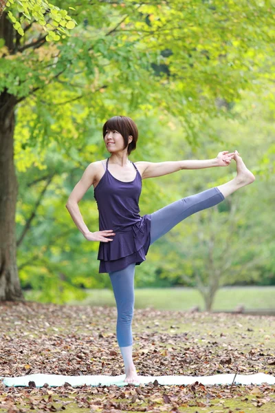 Guardar Descargar Previsualización Mujer japonesa afuera haciendo yoga Extended Hand-To-Big-Toe Pose —  Fotos de Stock