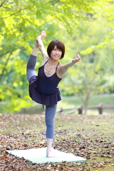 Guardar Descargar Previsualización Mujer japonesa afuera haciendo yoga Lord of the Dance Pose — Foto de Stock