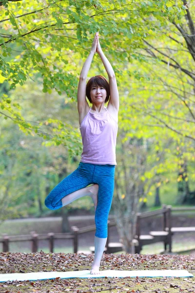 Japanese woman outside doing yoga tree pose — Stock Photo, Image