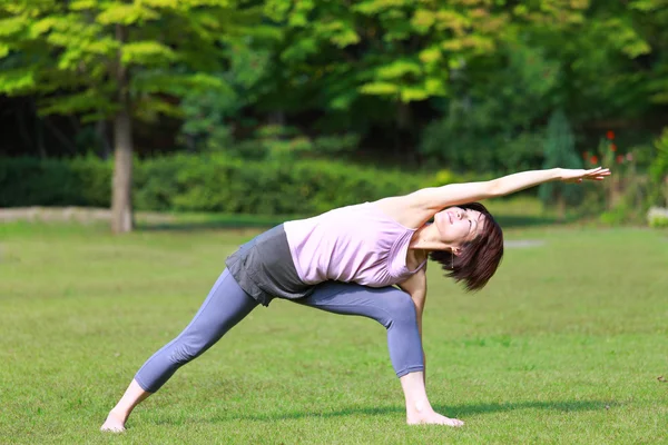 Japanerin draußen macht Yoga-Dreieck-Pose — Stockfoto