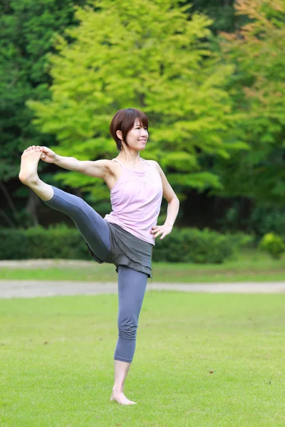 Salvar baixar visualização Mulher japonesa fora fazendo ioga estendido mão-a-grande-dedo do pé Pose — Fotografia de Stock