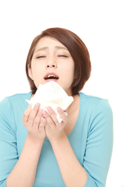 Young woman with an allergy sneezing into tissue — Stock Photo, Image