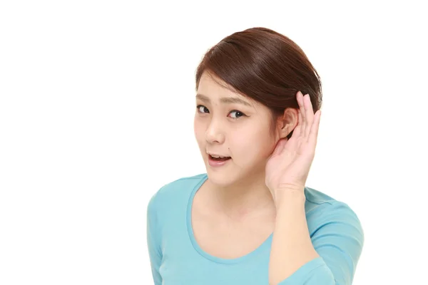Νεαρή γυναίκα με το χέρι πίσω από το αυτί ακούει προσεκτικά — Φωτογραφία Αρχείου