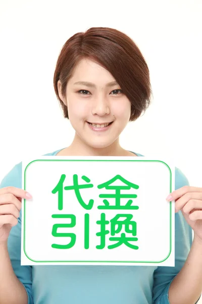 Donna che tiene una bacheca con la frase CASH ON DELIVERY in KANJI — Foto Stock