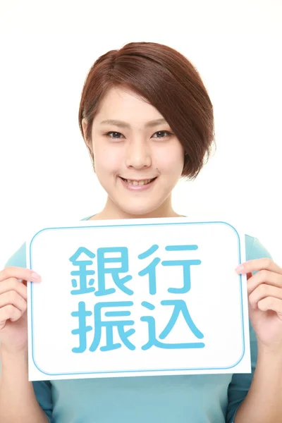 Woman holding a message board with the phrase BANK TRANSFER in KANJI — Stock Photo, Image
