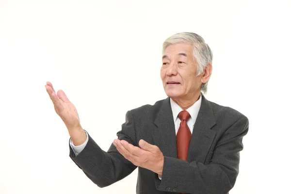 Empresário japonês sênior apresentando e mostrando algo — Fotografia de Stock