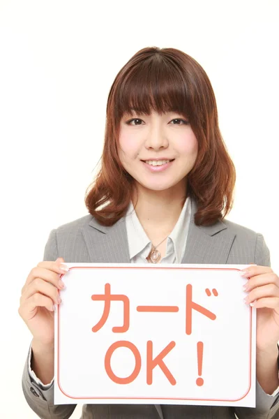 Businesswoman holding a message board with the phrase CREDIT CARD ACCEPTED in Japanese — Stock Photo, Image