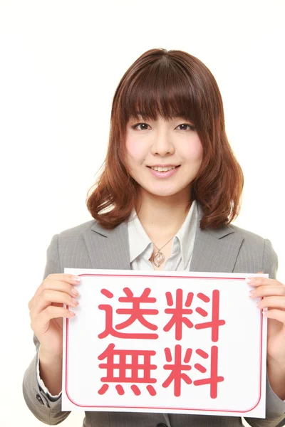 Affärskvinna innehar en anslagstavla med frasen gratis frakt i Kanji — Stockfoto