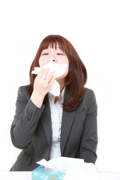 Young Japanese businesswoman with an allergy sneezing into tissue — Stock Photo, Image