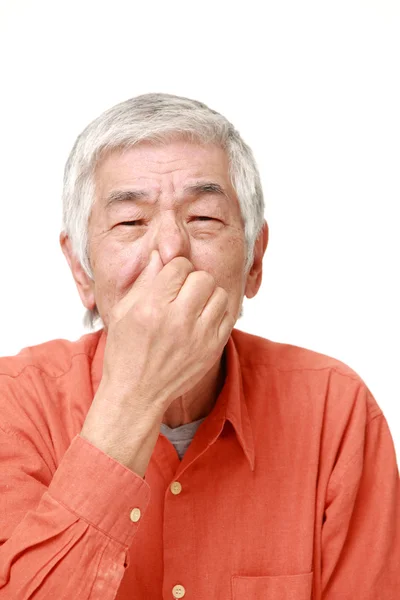 Старший японский мужчина держит нос из-за плохого запаха — стоковое фото