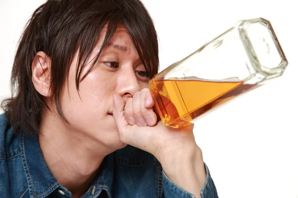 Young Japanese man drinking straight from a bottle — Stock Photo, Image