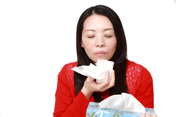Japanese woman with an allergy sneezing into tissue — Stock Photo, Image