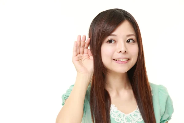 Junge Japanerin mit Hand hinter dem Ohr hört aufmerksam zu — Stockfoto