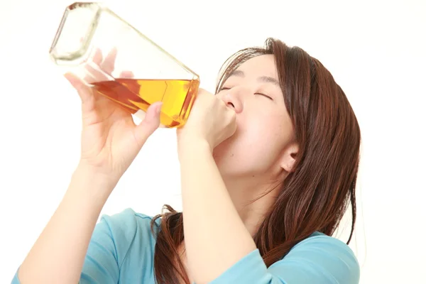 Middle aged Japanese Woman drinking straight from a bottle — Stock Photo, Image