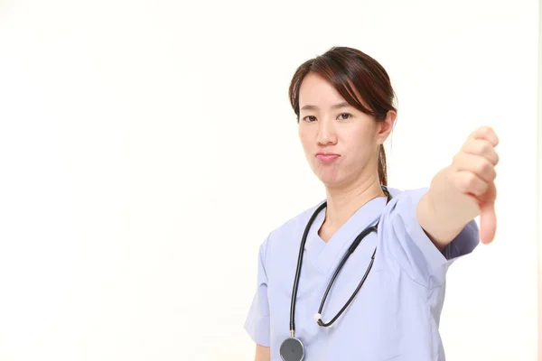 Japonesa mujer médico mostrando los pulgares hacia abajo gesto —  Fotos de Stock