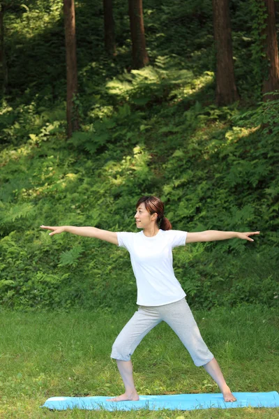 Japanese woman outside doing yoga warrior II pose — Stock Photo, Image