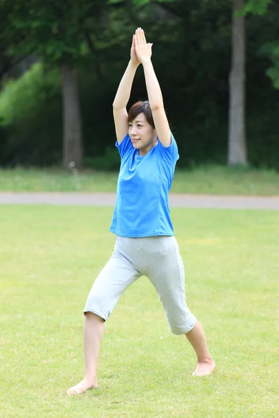 Japanese woman outside doing yoga warrior I pose — Stock Photo, Image