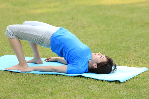 Japanese woman outside doing yoga Bridge Pose — Stock Photo, Image