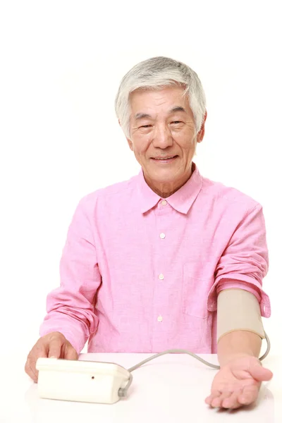 シニアの日本人男性が自分の血圧をチェック — ストック写真