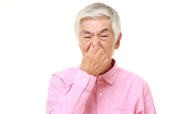 Старший японський чоловік тримає його ніс через поганий запах — стокове фото