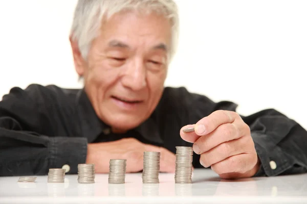Senior japonais homme mettre des pièces à pile de pièces — Photo