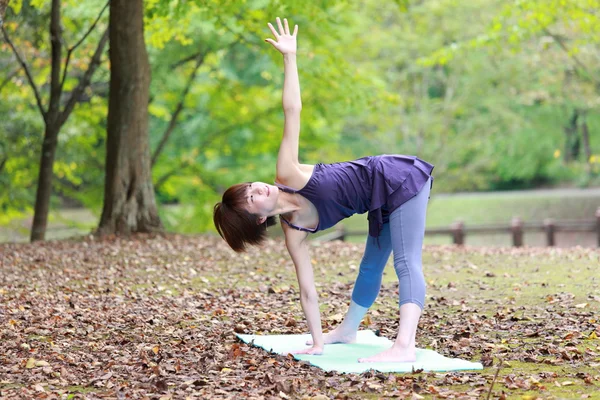 Japanese woman outside doing yoga revolved triangle pose — Stock Photo, Image