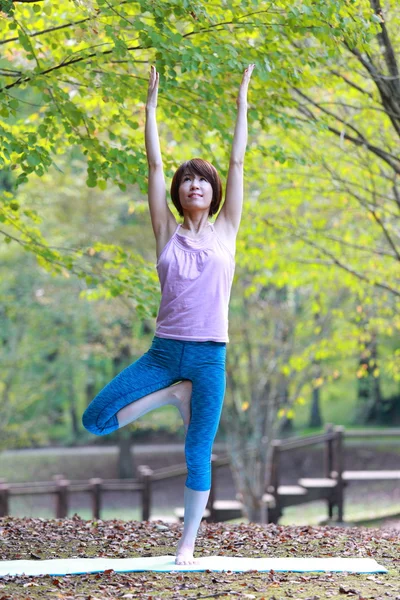 Japonês mulher fora fazendo ioga árvore pose — Fotografia de Stock