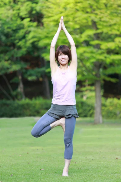 Japonesa mujer fuera haciendo yoga árbol pose — Foto de Stock