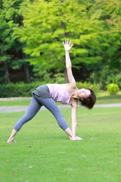 Japanese woman outside doing yoga revolved triangle pose — Stock Photo, Image