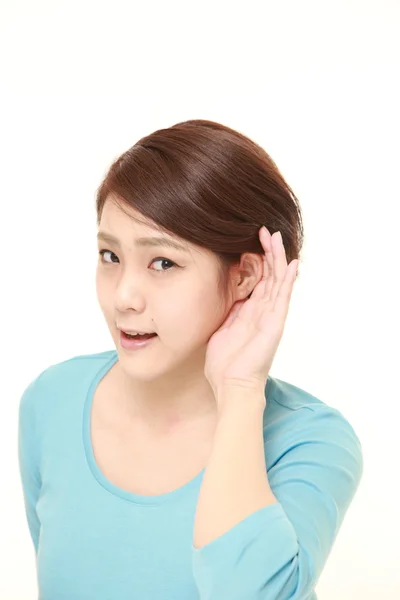 Ung kvinna med handen bakom örat lyssnar noga — Stockfoto